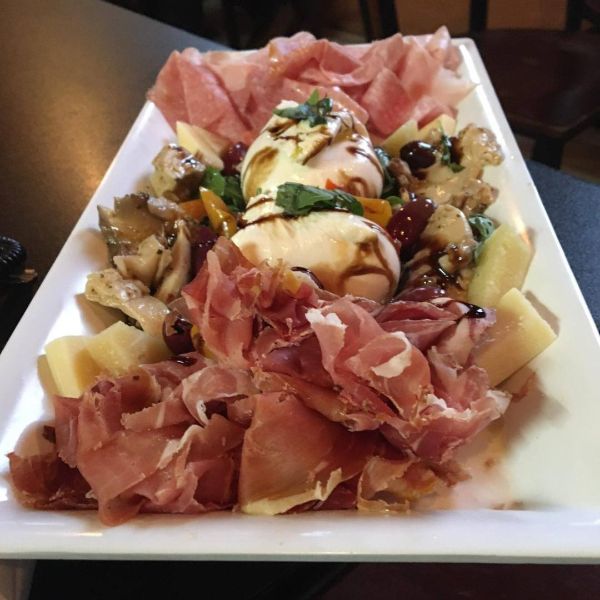 A white plate with a variety of meats and cheeses on it.
