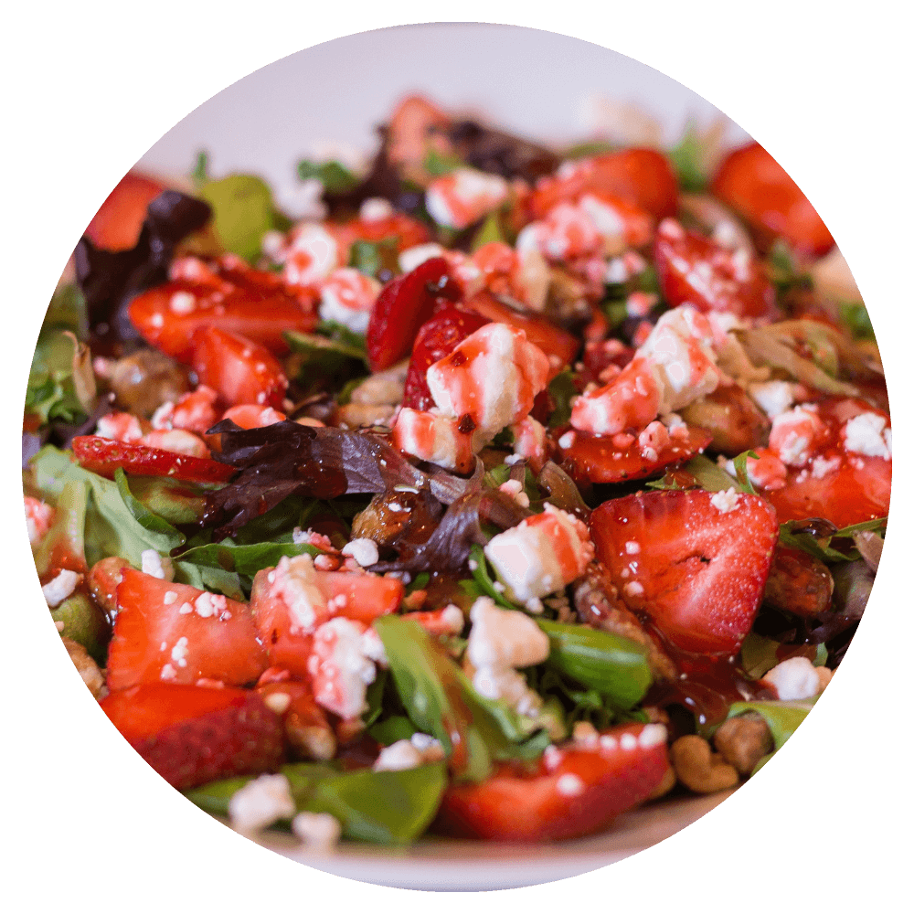A salad with strawberries, nuts and feta on a white plate.
